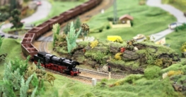 H0-Modellbahnlandschaft mit Dampflok und bewachsenen Hügeln